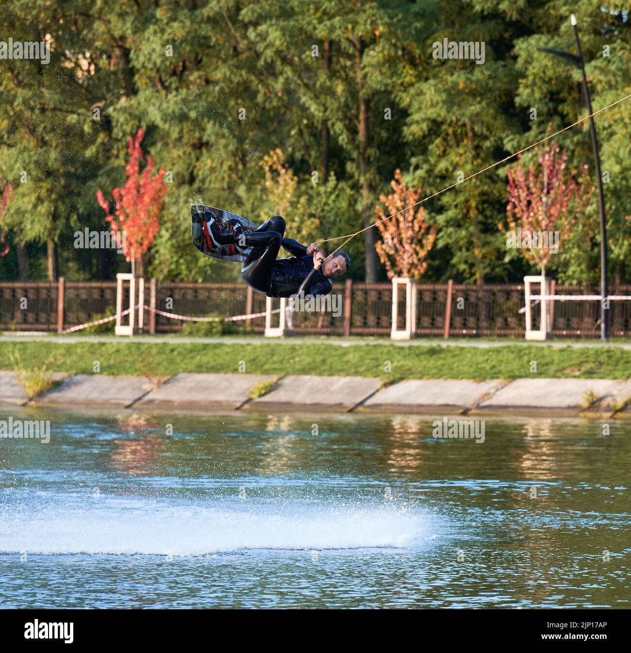 Wakeboarder making tricks while wakeboarding on lake. Young man surfer having fun wakesurfing in