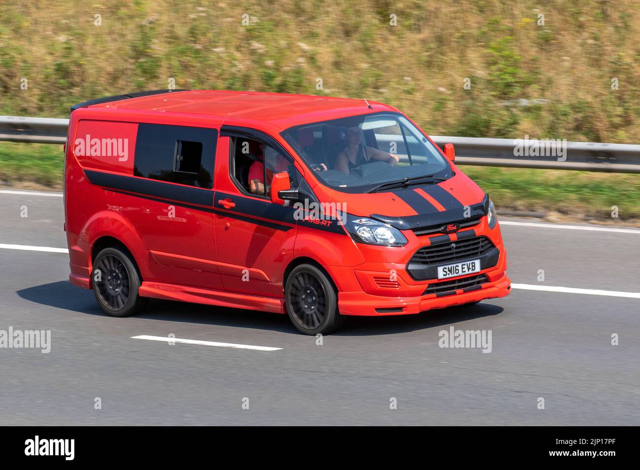 2016 red Ford Transit Custom 270 Eco-Tech, LCV Panel Van; moving cars, being driven, in motion, travelling on the M6 motorway, UK Stock Photo