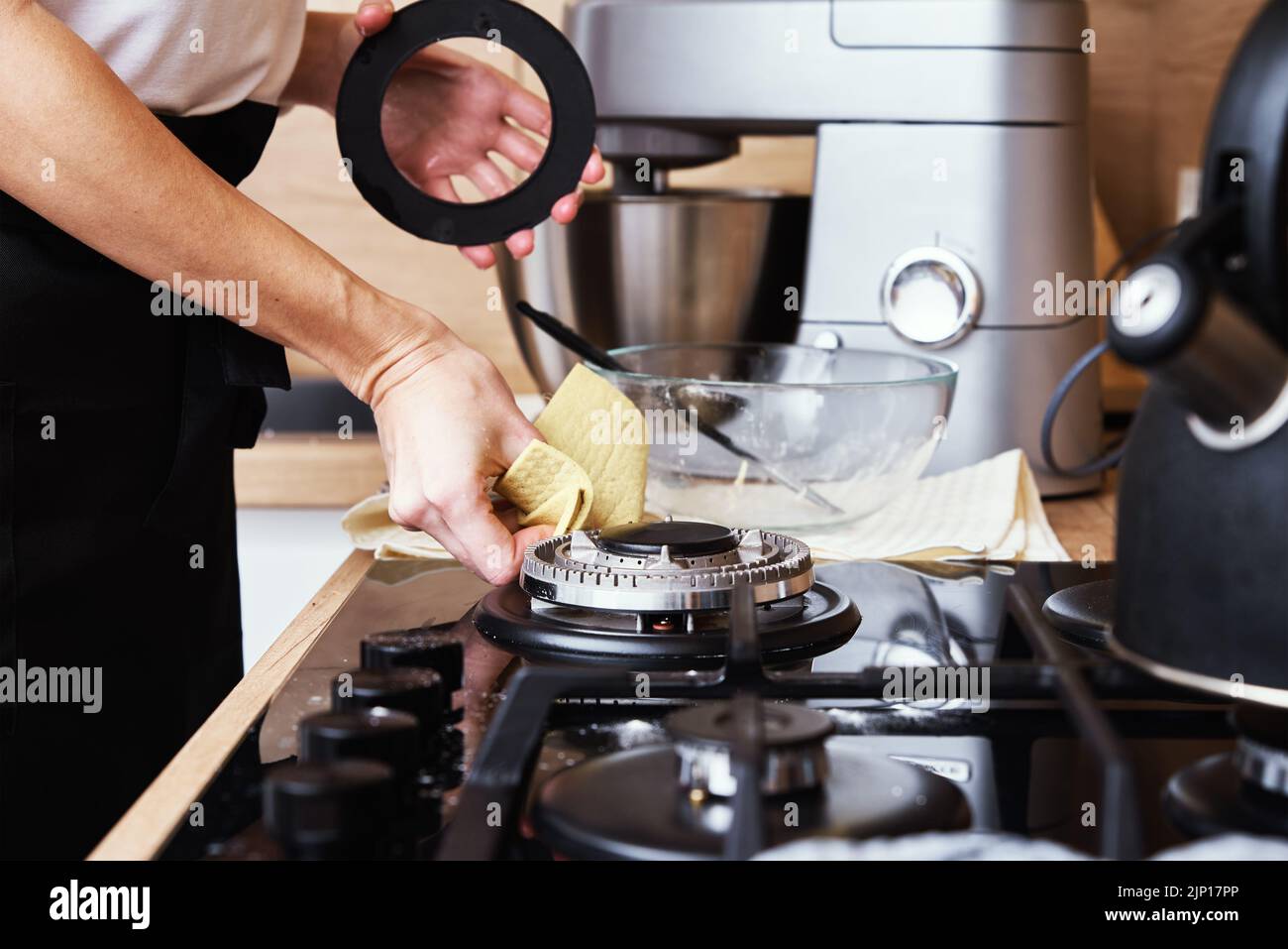 Cleaning gas stove. Woman cleans kitchen gas hob with cleaning sponge