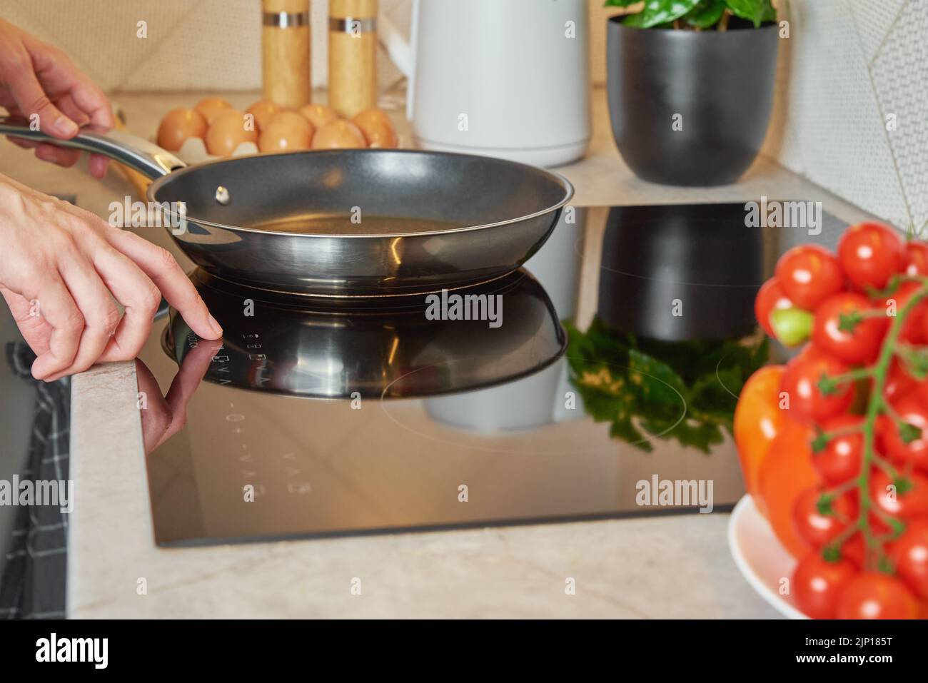 Modern kitchen appliance, Woman hand turn on induction stove with steel frying pan, Finger