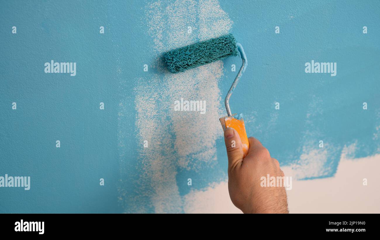 Decorator hand painting walls in blue color with roller Stock Photo Alamy