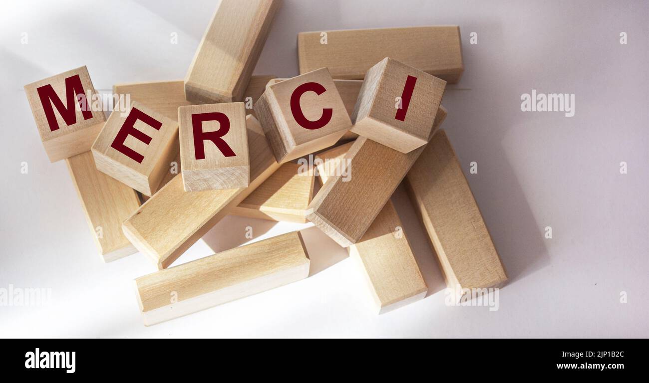 Merci - Thank you in French. The word Merci on wooden cubes on a white background. Stock Photo