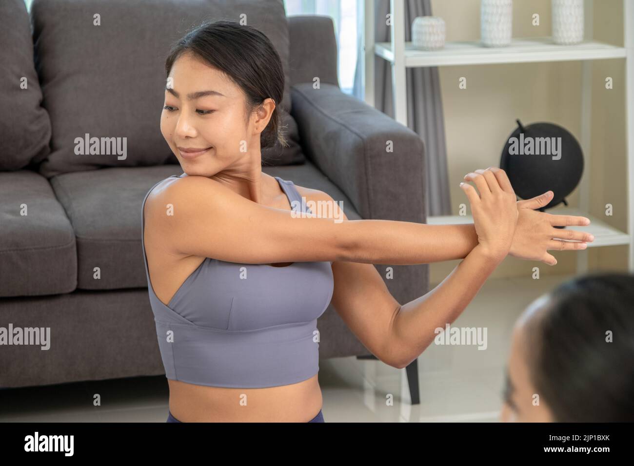 Asian people practicing yoga lifestyle class on a mat at living room. Young women with sports ware teach how to exercise yoga training at home Stock Photo