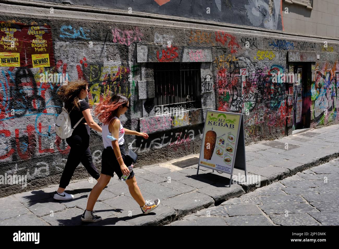 Two females walking past graffiti in Naples, Napoli, Italy Stock Photo