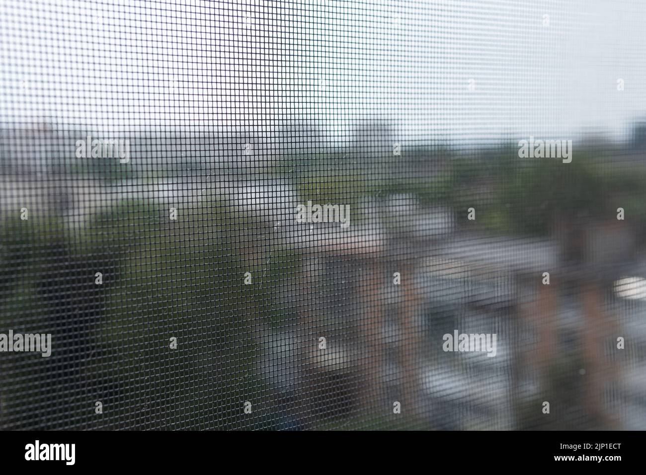 Blurred view of the city through an insect mesh on a house or apartment window. A mosquito net. Protection of housing from insects. Safety. Stock Photo