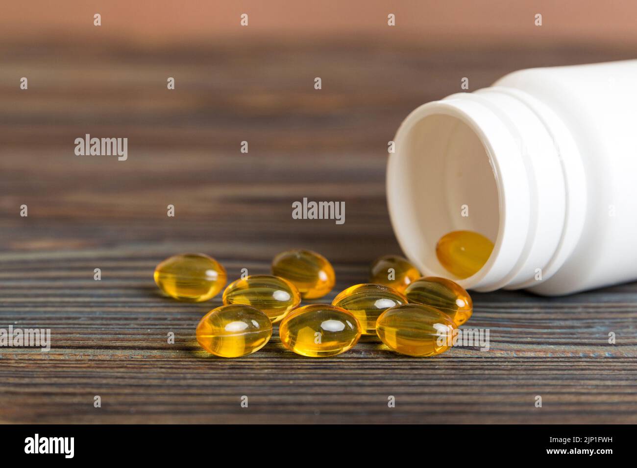 Soft gels pills with Omega3 oil spilling out of pill bottle closeup