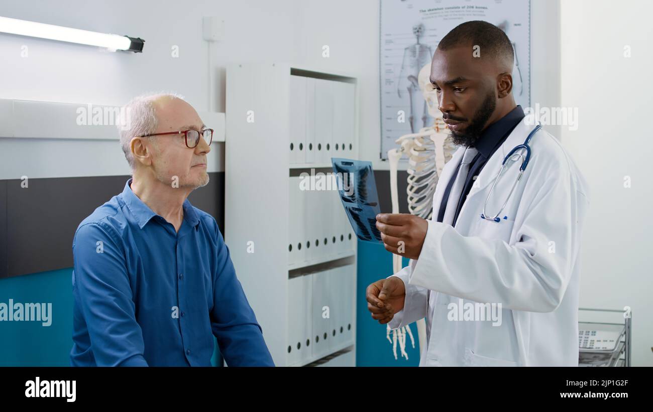 Male doctor showing radiography results to senior man in medical office
