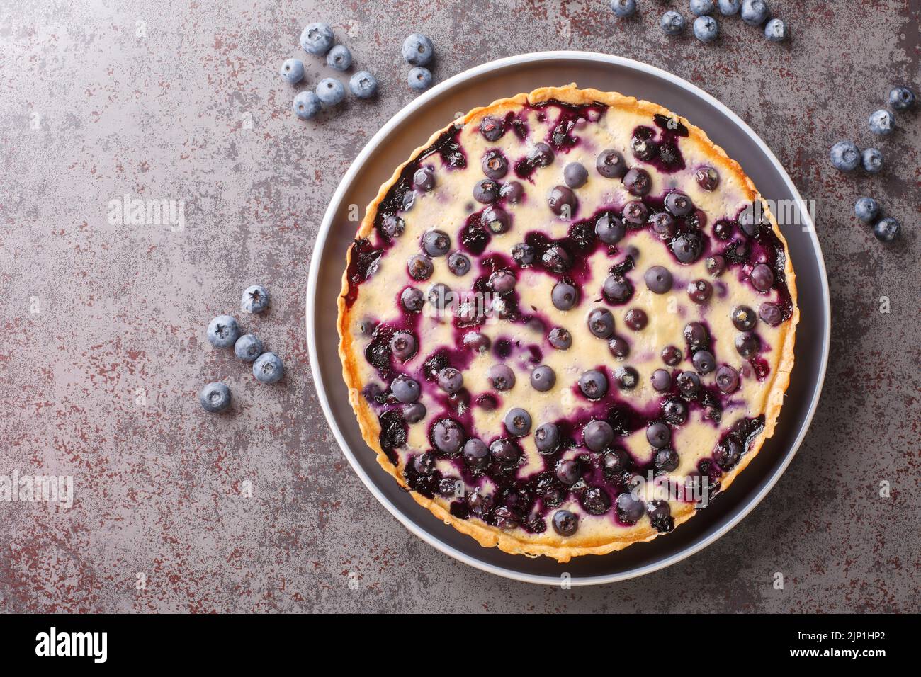 Delicious blueberry tart with custard and crispy crust close-up in a plate on the table. Horizontal top view from above Stock Photo