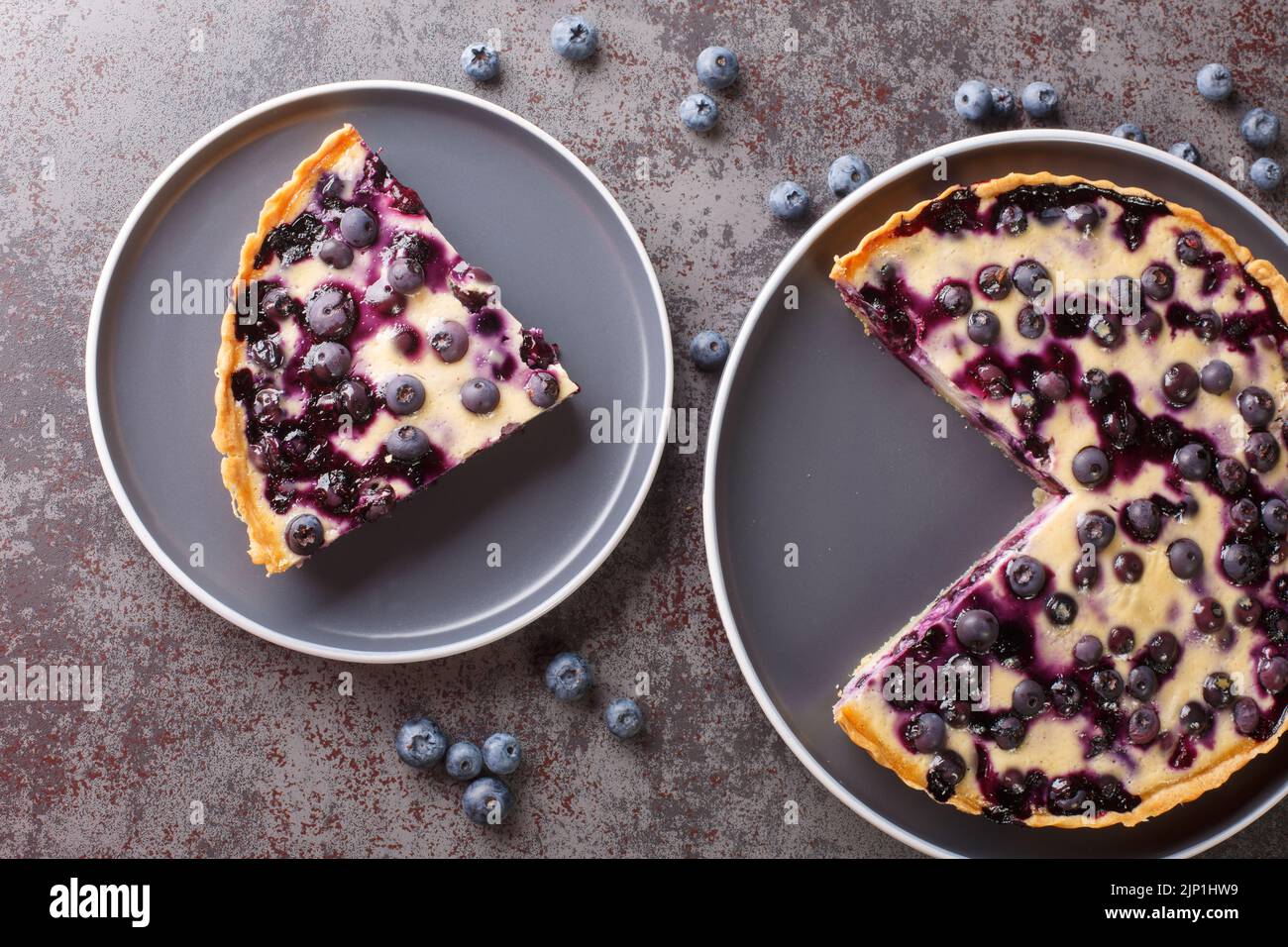 Homemade fresh blueberry tart with custard close-up in a plate on the table. Horizontal top view from above Stock Photo