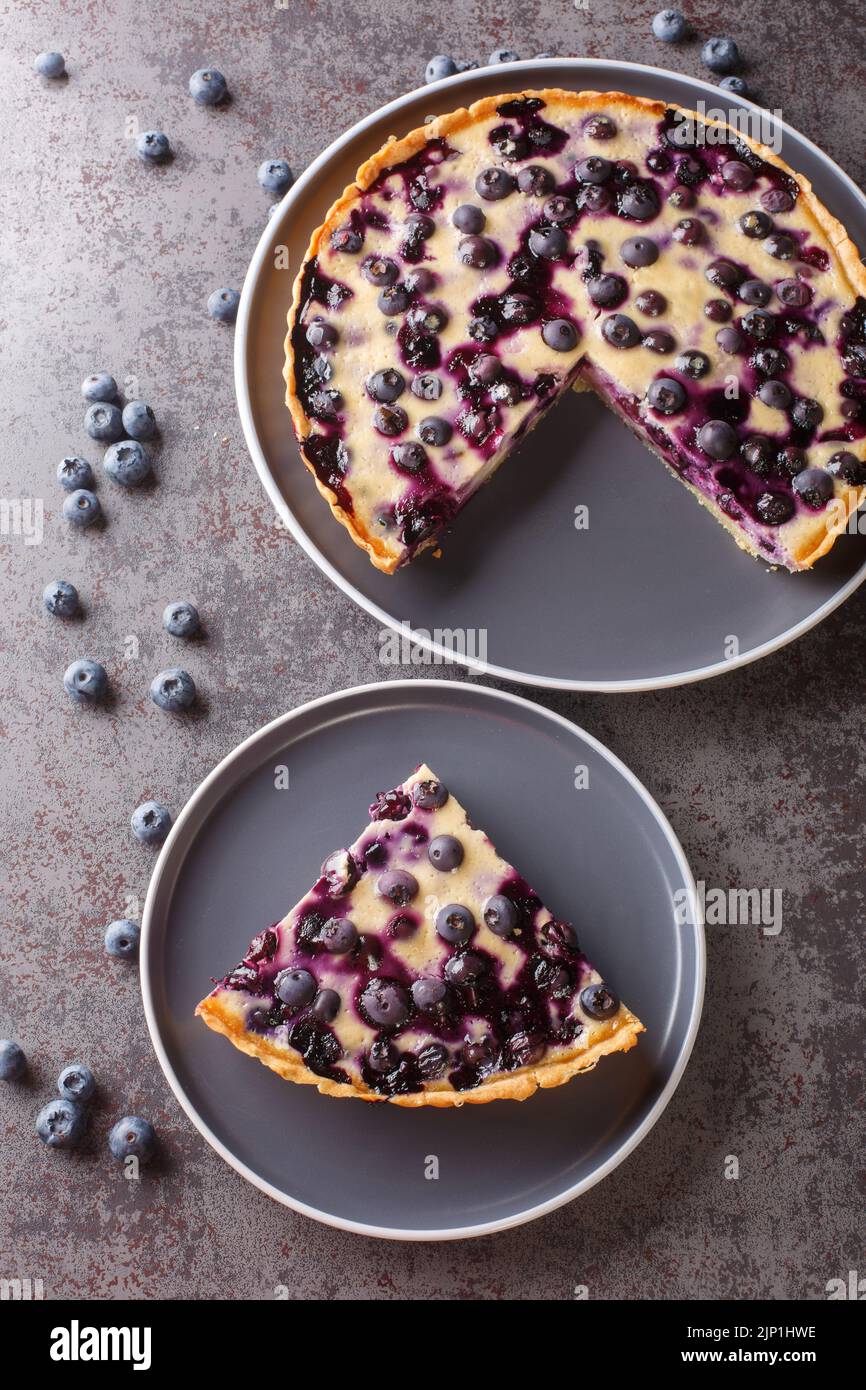 Sliced Mustikkapiirakka Finnish Blueberry Pie close-up in a plate on a table. Vertical top view from above Stock Photo