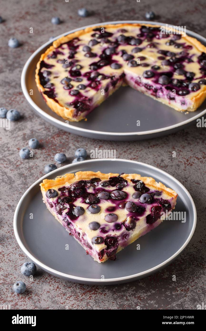 Sliced Mustikkapiirakka Finnish Blueberry Pie close-up in a plate on a table. Vertical Stock Photo