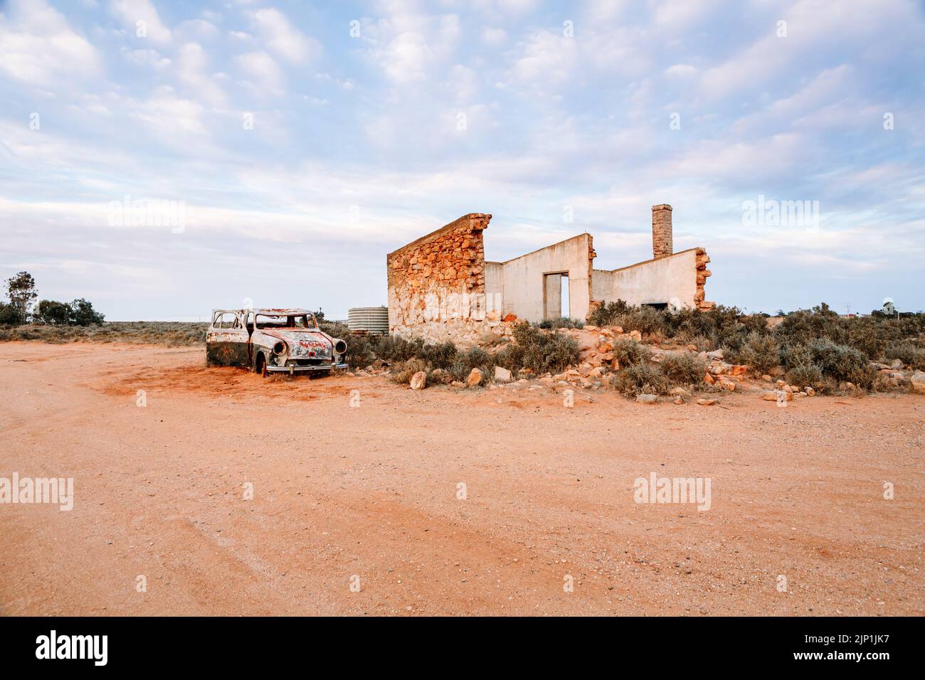 Crumbling old stone homes and rusting cars in outback Australia Stock Photo