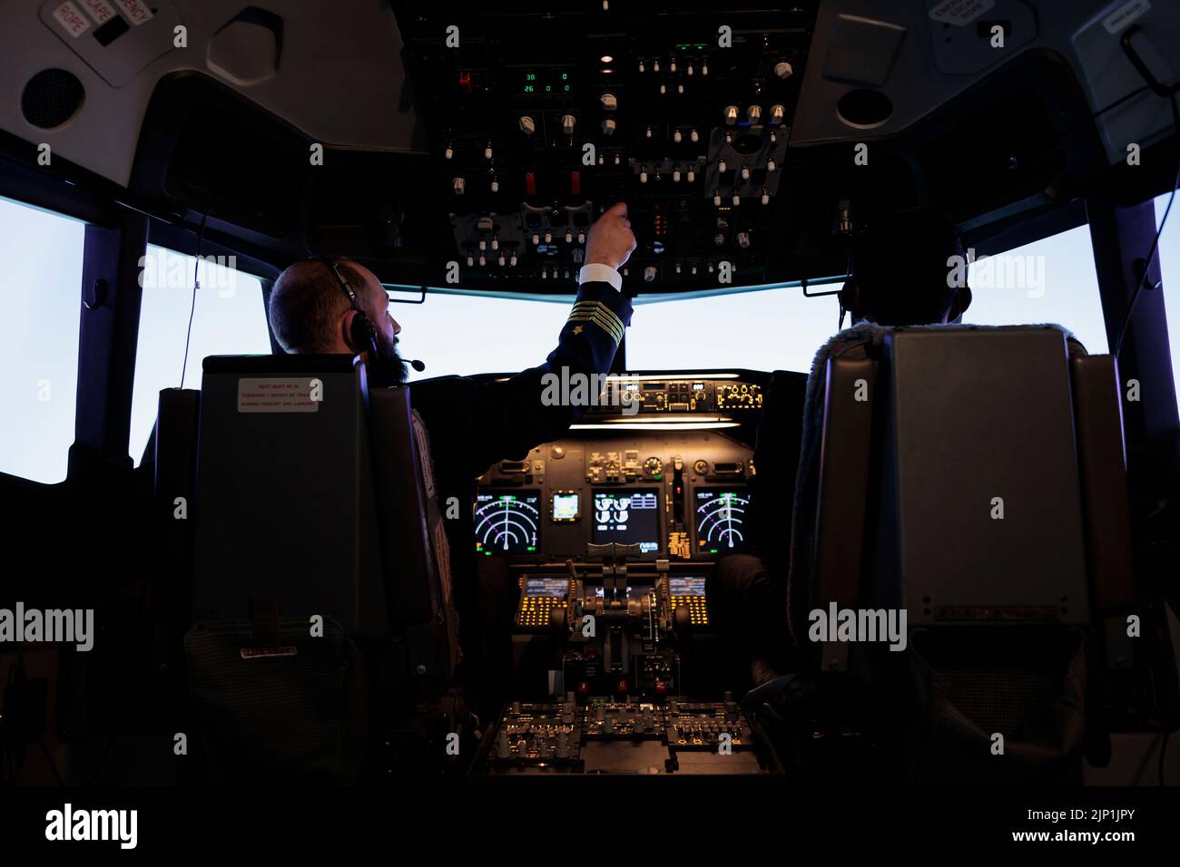 Male captain pushing dashboard buttons in plane cockpit, flying