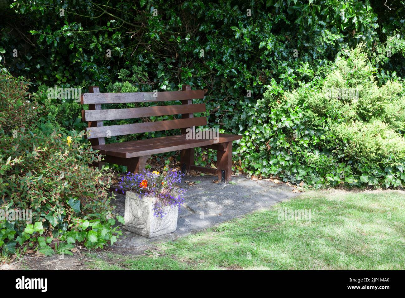 Bench on the village green, Rhu, Nr Helensburgh, Scotland, with pot of annual flowers, Stock Photo