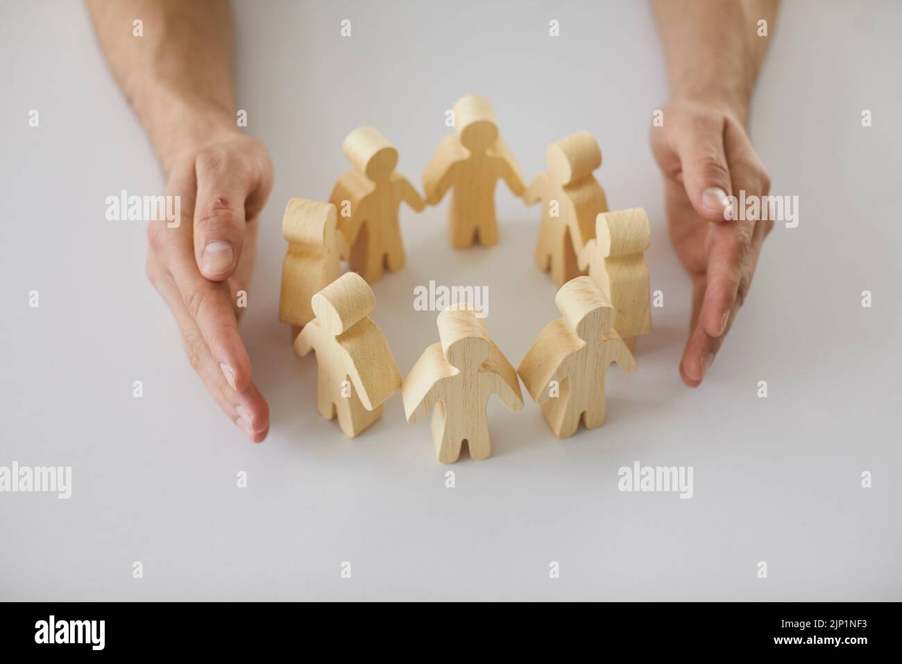 Hands protecting human figures as metaphor for creating safe community of people Stock Photo