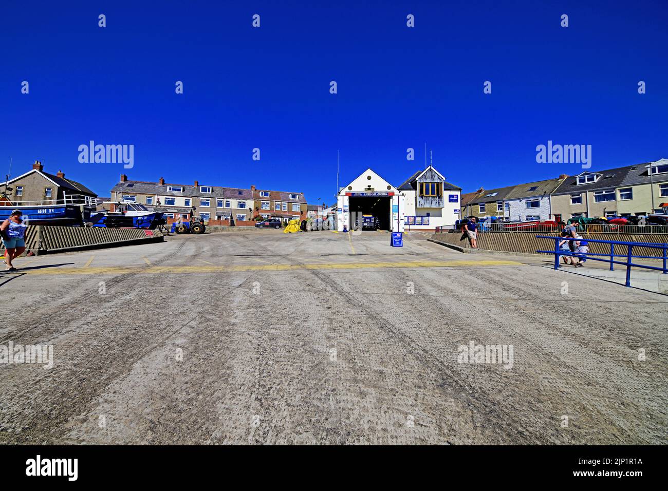 Newbiggin by the sea Northumberland beautiful seaside village with the RNLI station by the long promenade and concrete runway against a deep blue summ Stock Photo