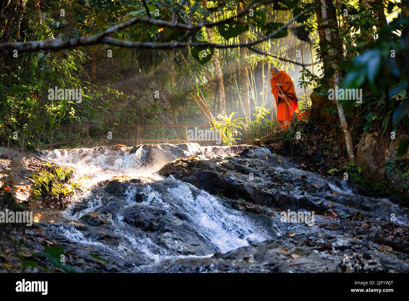 MAE KAMPONG, THAILAND - 22 JANUARY 2022 : A Buddhist monk is cleaning the ground early morning near the little temple along the river . Stock Photo