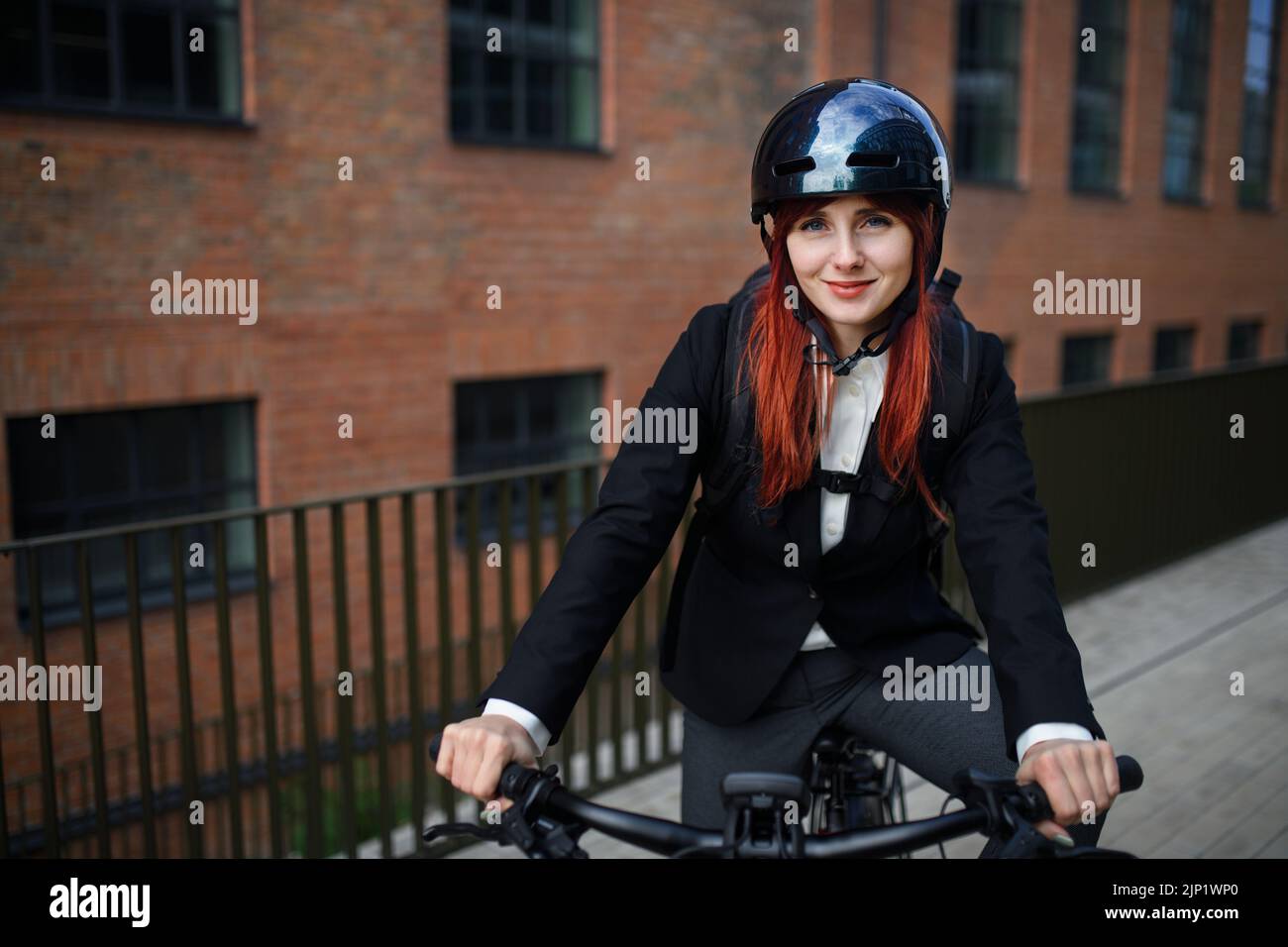 Portrait of businesswoman commuter on the way to work with bike, sustainable lifestyle concept. Stock Photo