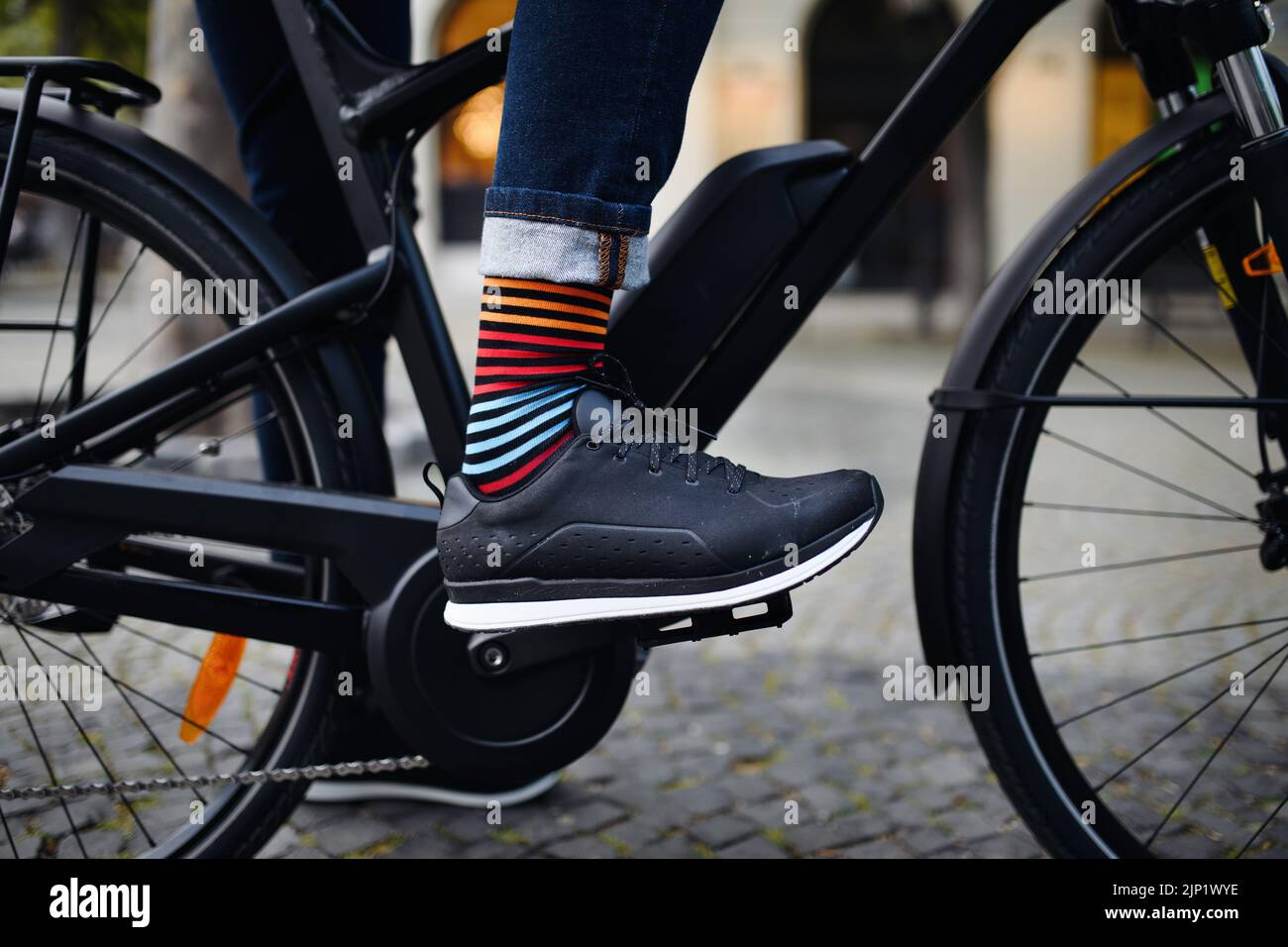 Businessman commuter on the way to work, close up of his legs riding bicycle. Stock Photo