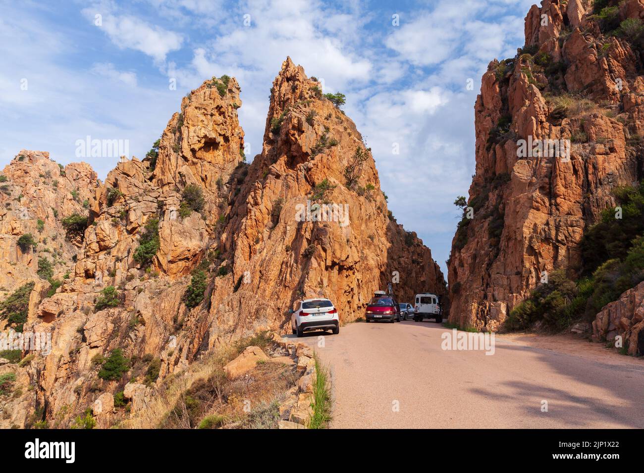 Corsica, France - August 23, 2018: Cars are on the narrow mountain road at the Calanques de Piana. Corsican landscape with rocks located in Piana, bet Stock Photo