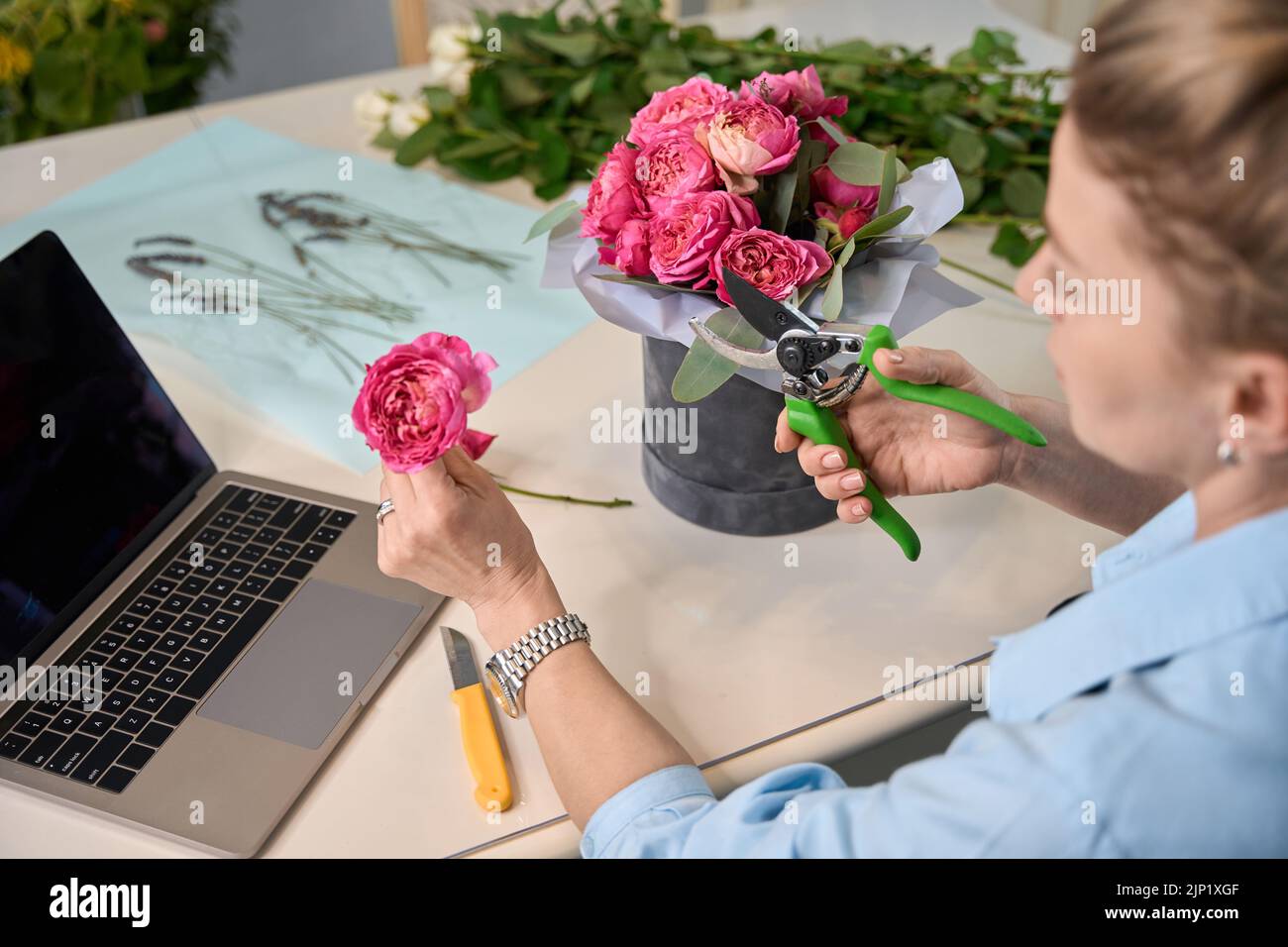 Charming female florist teaches to create flower arrangements in box Stock Photo