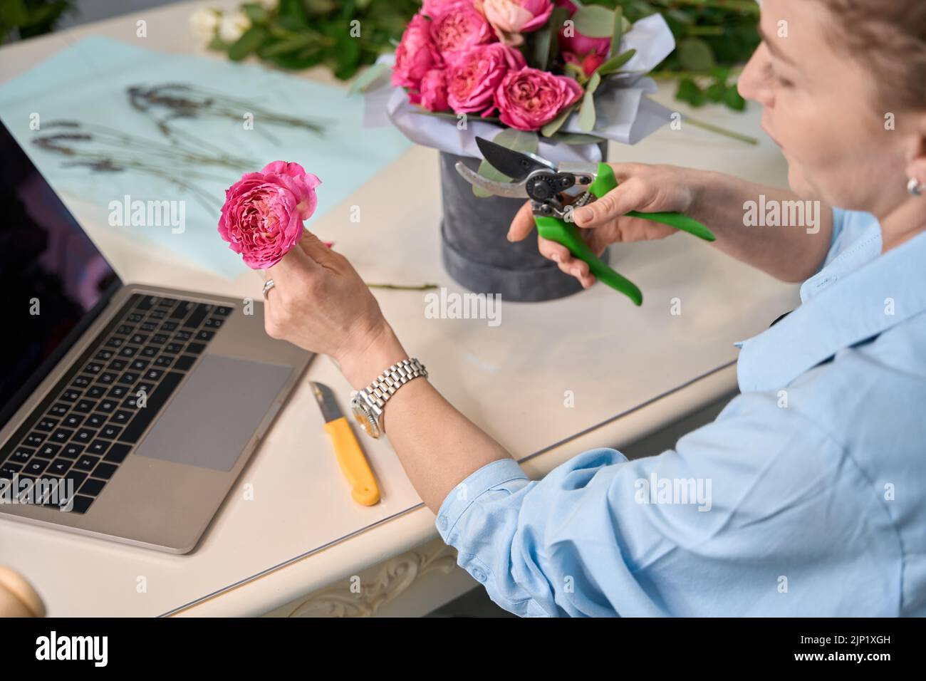 Nice woman florist teaches to create flower bouquet in box Stock Photo