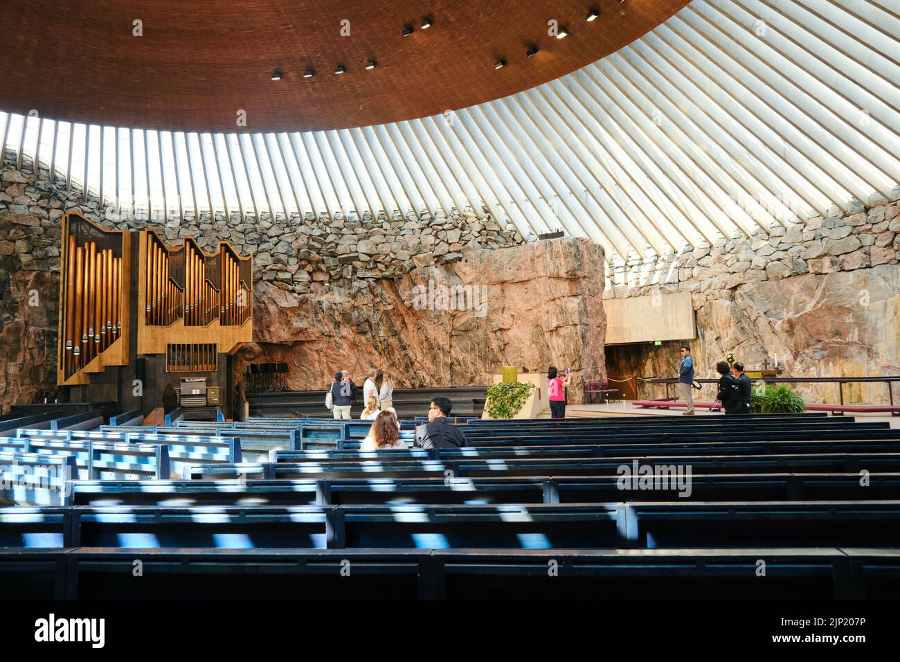 Helsinki, Finland - 10 August 2022: Interior of famous Temppeliaukio church built directly into solid rock with walking tourists in Helsinki, Finland Stock Photo