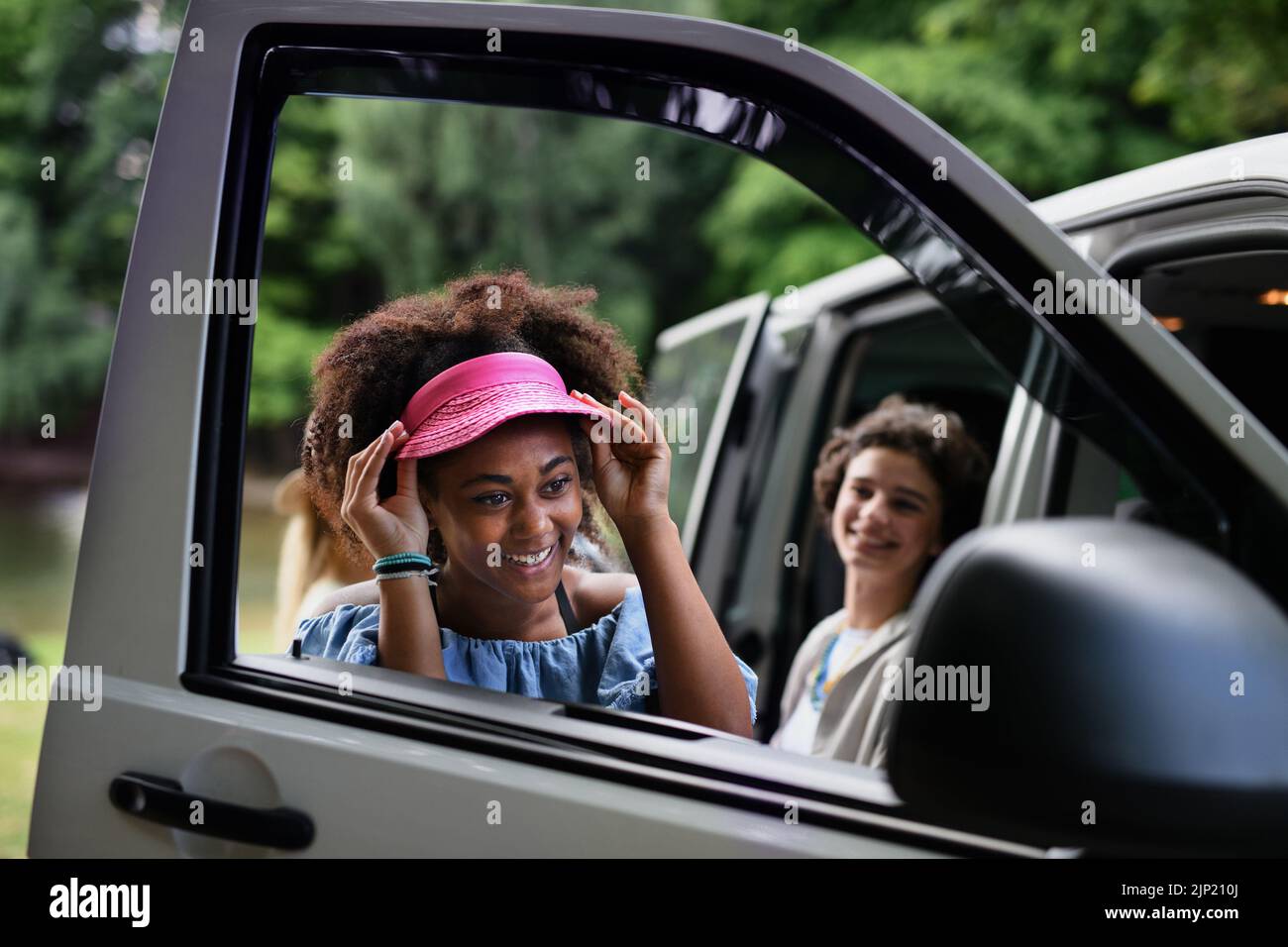 Young multiracial woman looking in the car mirror and checking her visage. Stock Photo