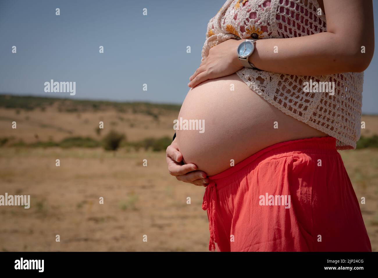 outdoors close up tummy of woman enjoying summer holiday while pregnant holding her  belly happy and proud as mother expecting baby concept Stock Photo