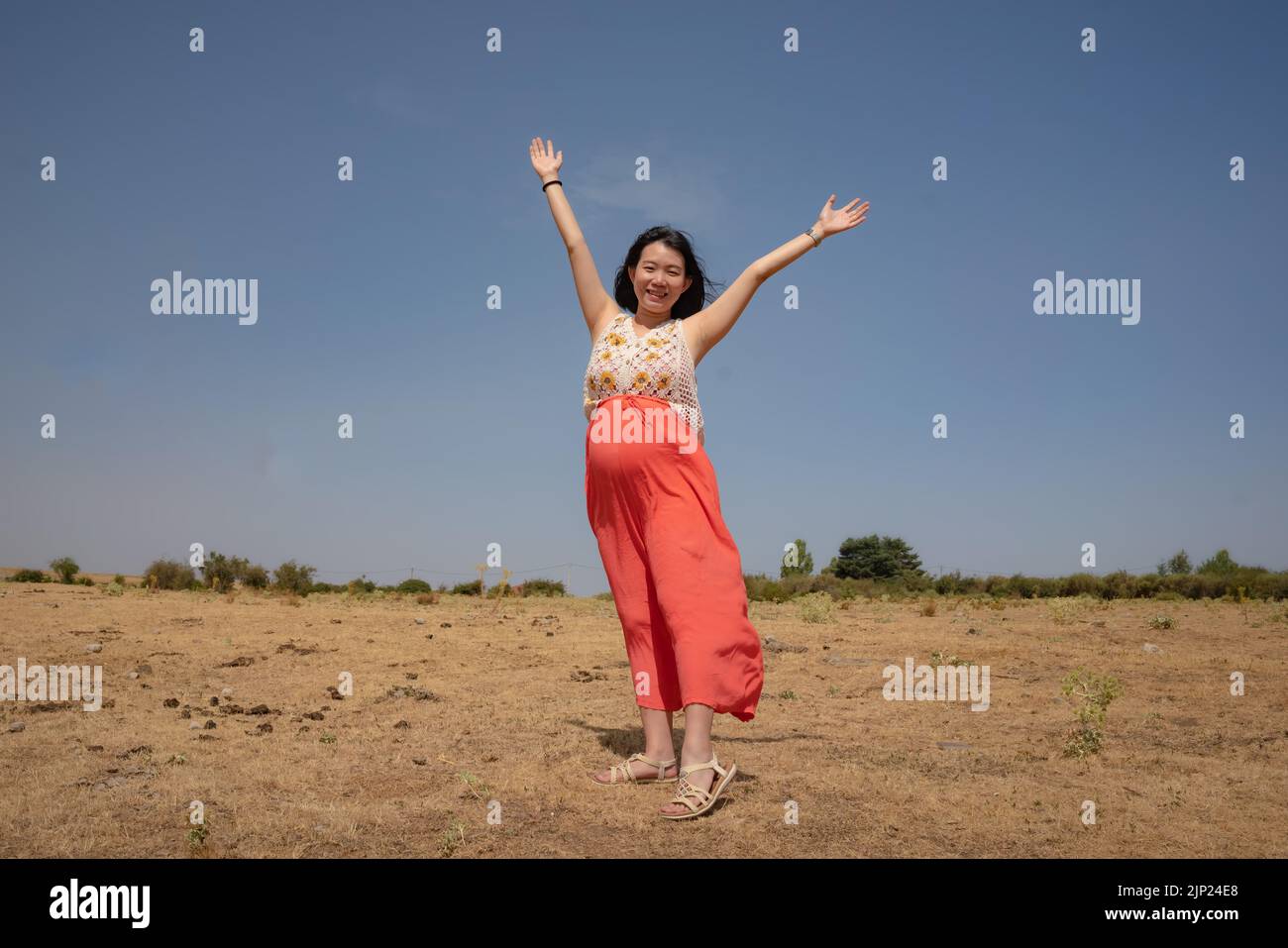 outdoors lifestyle portrait of young happy and beautiful Chinese woman enjoying summer holiday while pregnant proud of her belly as mother expecting b Stock Photo