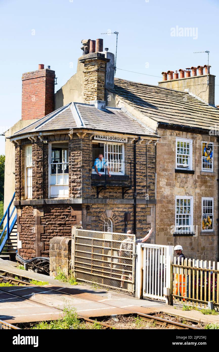 Signal box, crossing gate at Knaresborough Station on the York Leeds line. With signalman talking to pedestrian. Stock Photo