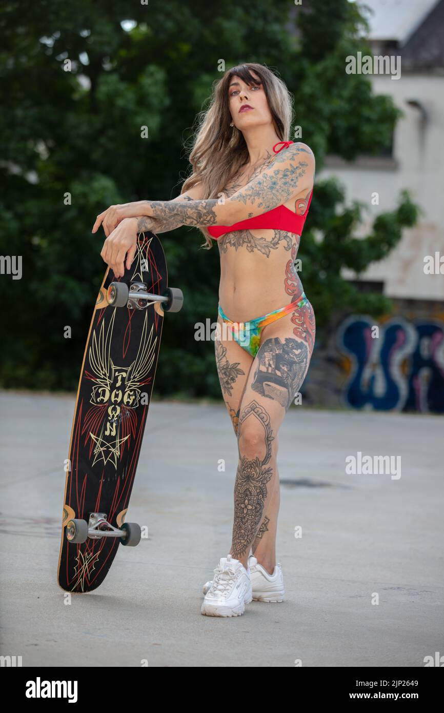 a beautifull tattooed model with skateboard/longboard, in bikini, skateboarding at the skatepark Stock Photo