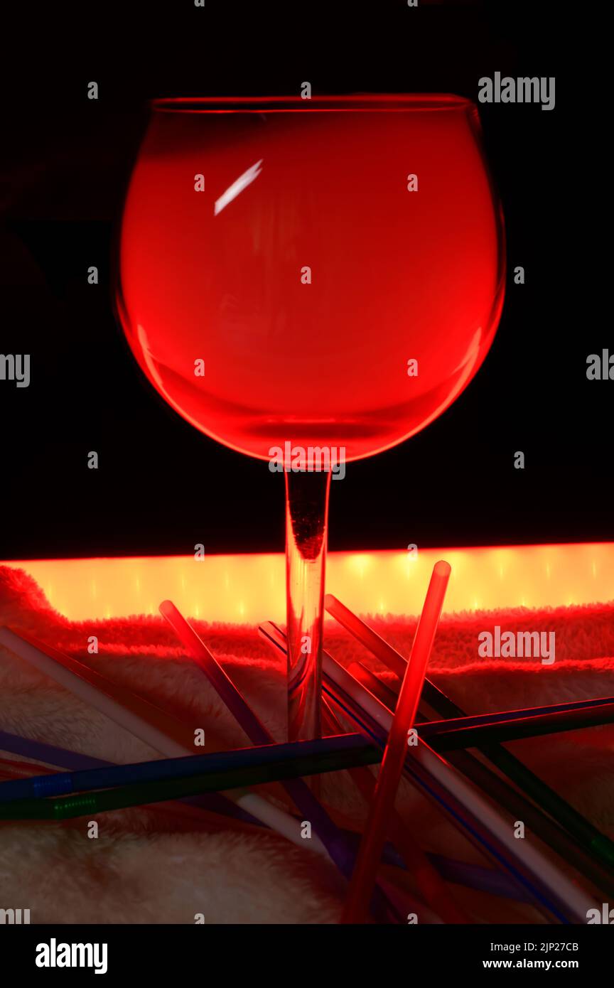 One Glass of a Red Alcoholic Cocktail on soft blanket with straws, smoke and backlight. Very