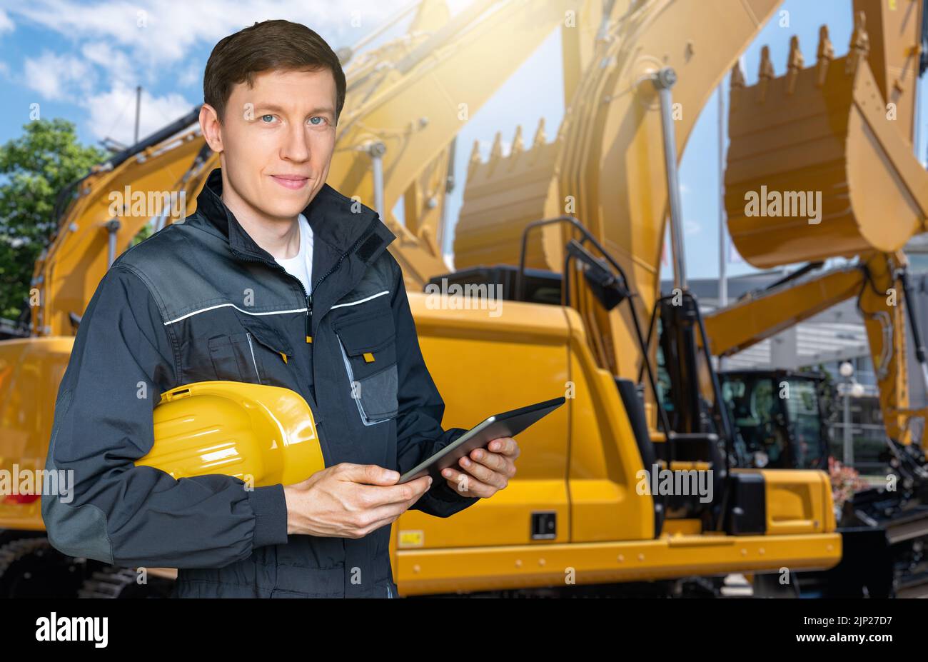 Engineer in a helmet with a digital tablet on the background of construction machines Stock Photo