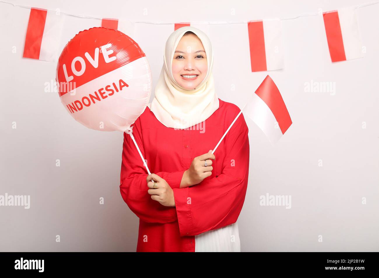 portrait of beautiful young asian woman with indonesian flag and balloon of indonesia independence day on isolated white background Stock Photo