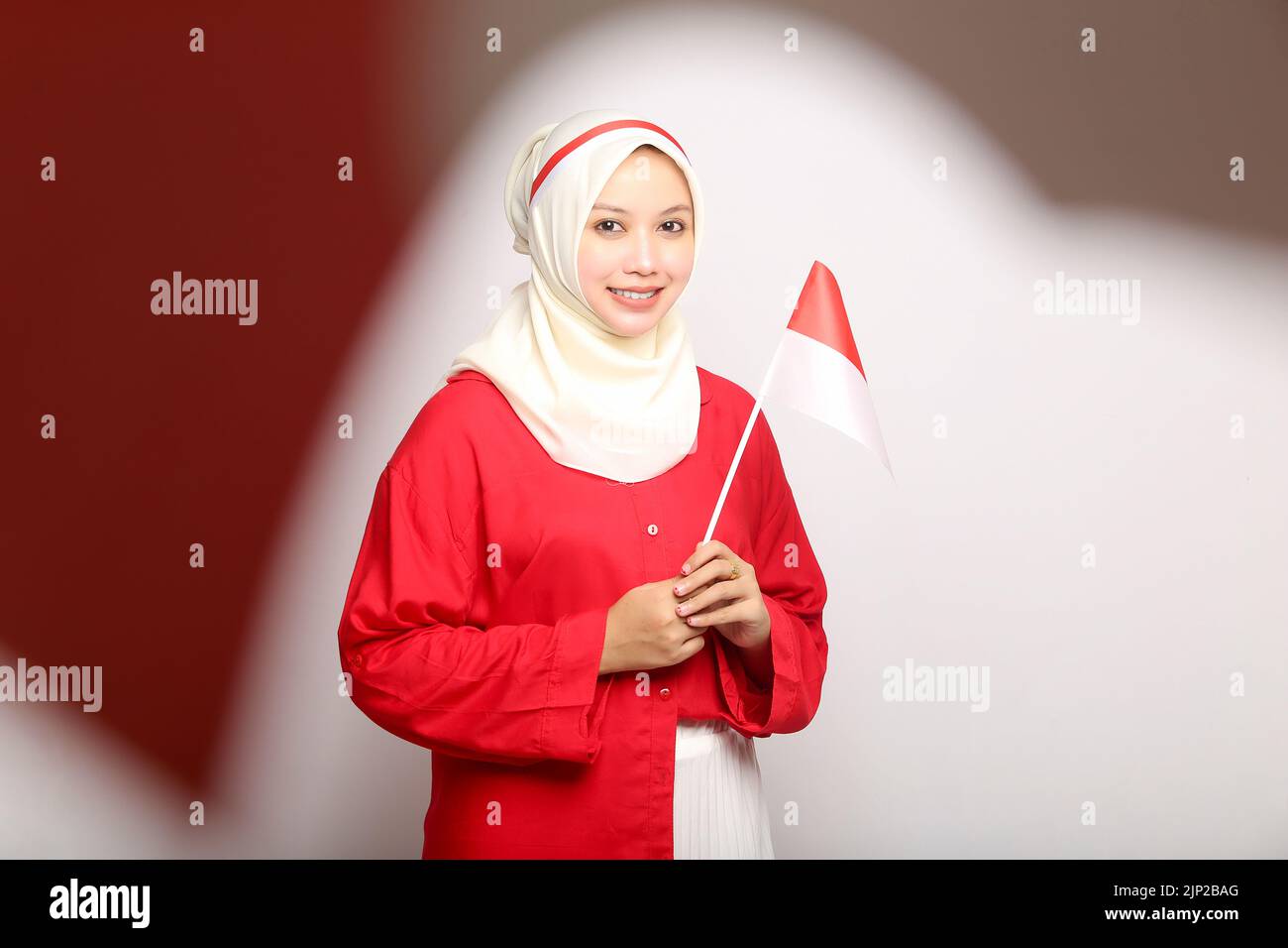 Beautiful Portrait Asian young woman holding indonesian flag of indonesia independence day on isolated white background Stock Photo