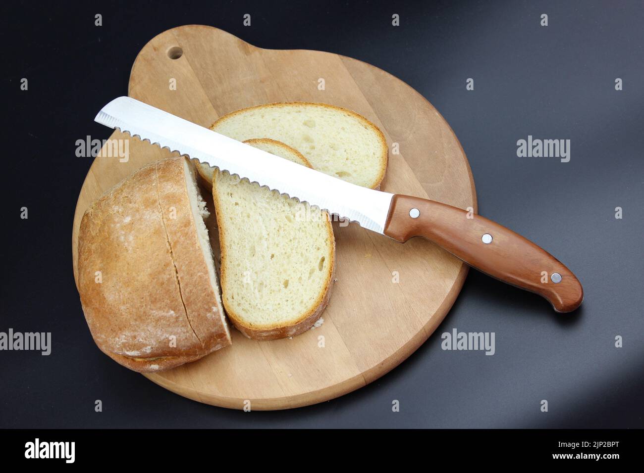 Knife is cutting a loaf of bread into slices. Seed bread, homemade bread,cutting bread Stock Photo