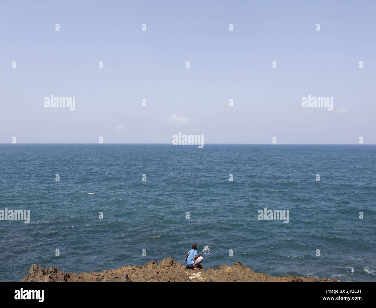 A person sitting on the edge of the cliff looking at the sea Stock ...