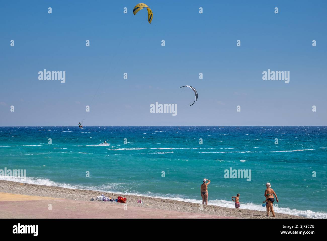 kitesurfers surfing and jumping in the air with people staring of them from the shore of Agiokampos beach,Greece Stock Photo