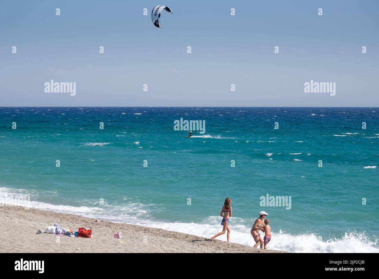 Man kitesfring with people and a family playing in  the shore of Agiokampos beach,Greece Stock Photo