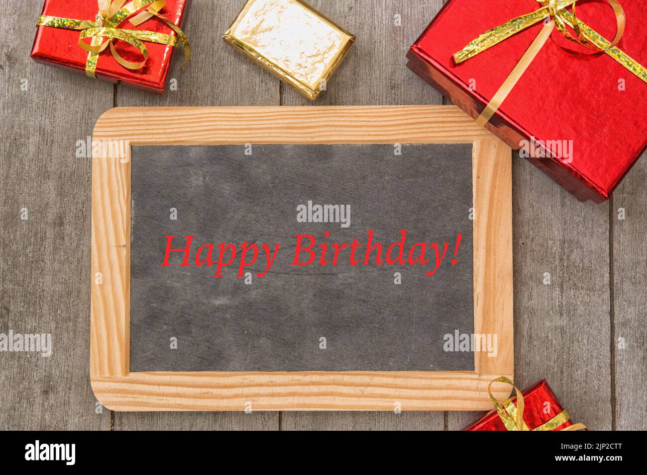 Red and gold gift boxes with over wooden background with blackboard Stock Photo