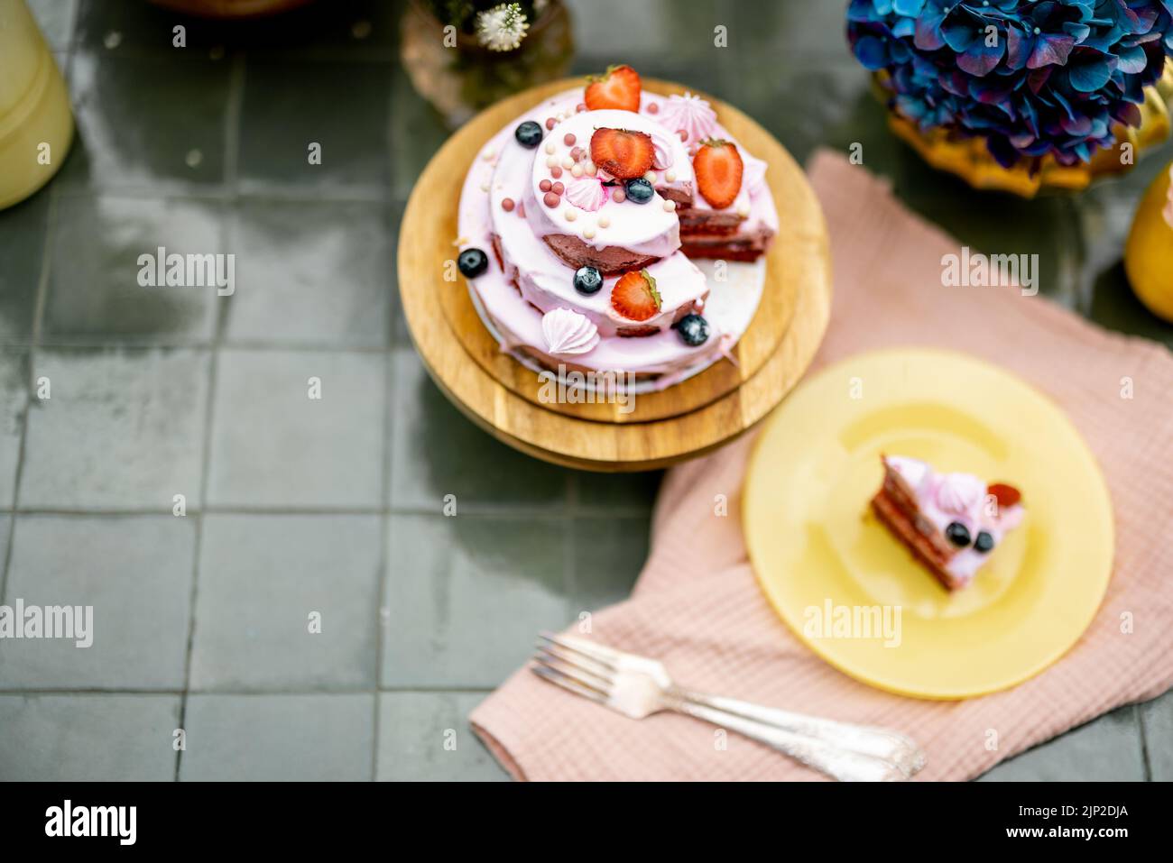 Beautiful tiled table served with festive berry cheesecake and decorated with flowers, view from above. Sweet holiday concept Stock Photo