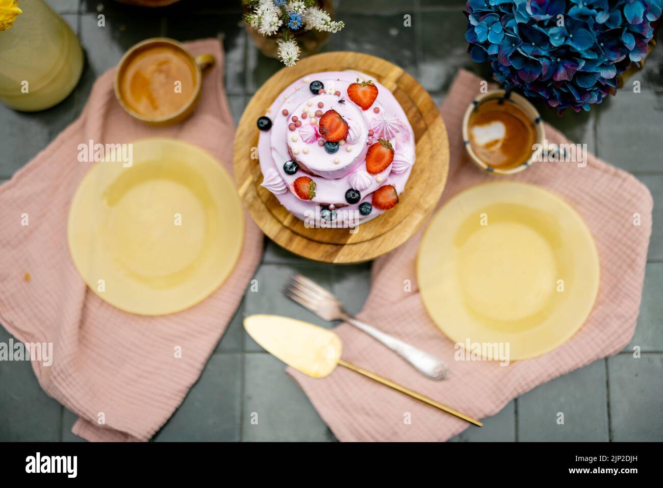 Beautiful tiled table served with festive berry cheesecake and decorated with flowers, view from above. Sweet holiday concept Stock Photo