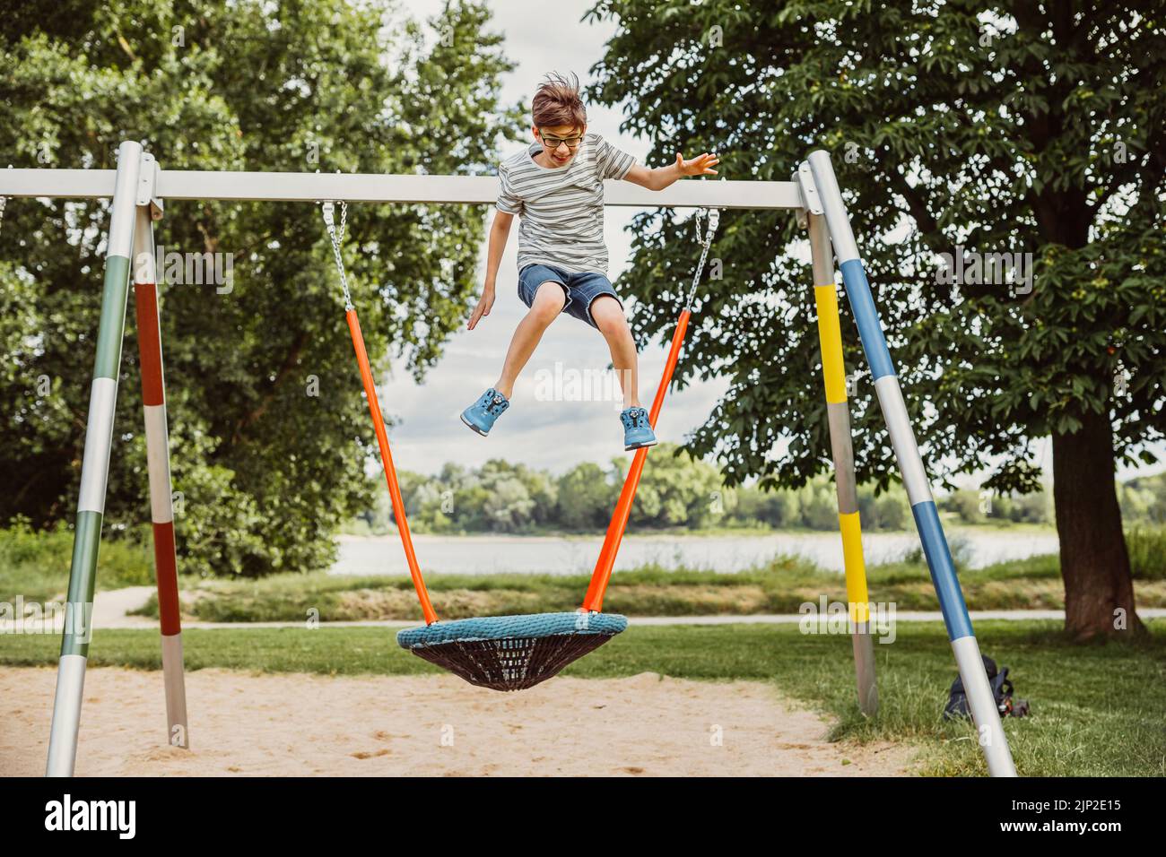 A boy jumping off from net swing and fly away from ground Stock Photo