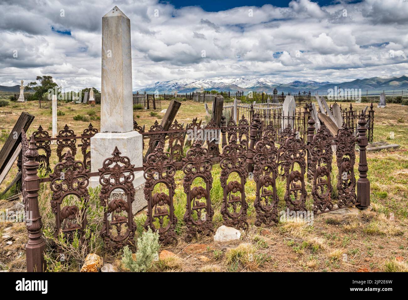 Wrought iron fence at tombstone at cemetery in ghost town of Tuscarora, Independence Valley, Independence Mountains in distance, Nevada, USA Stock Photo