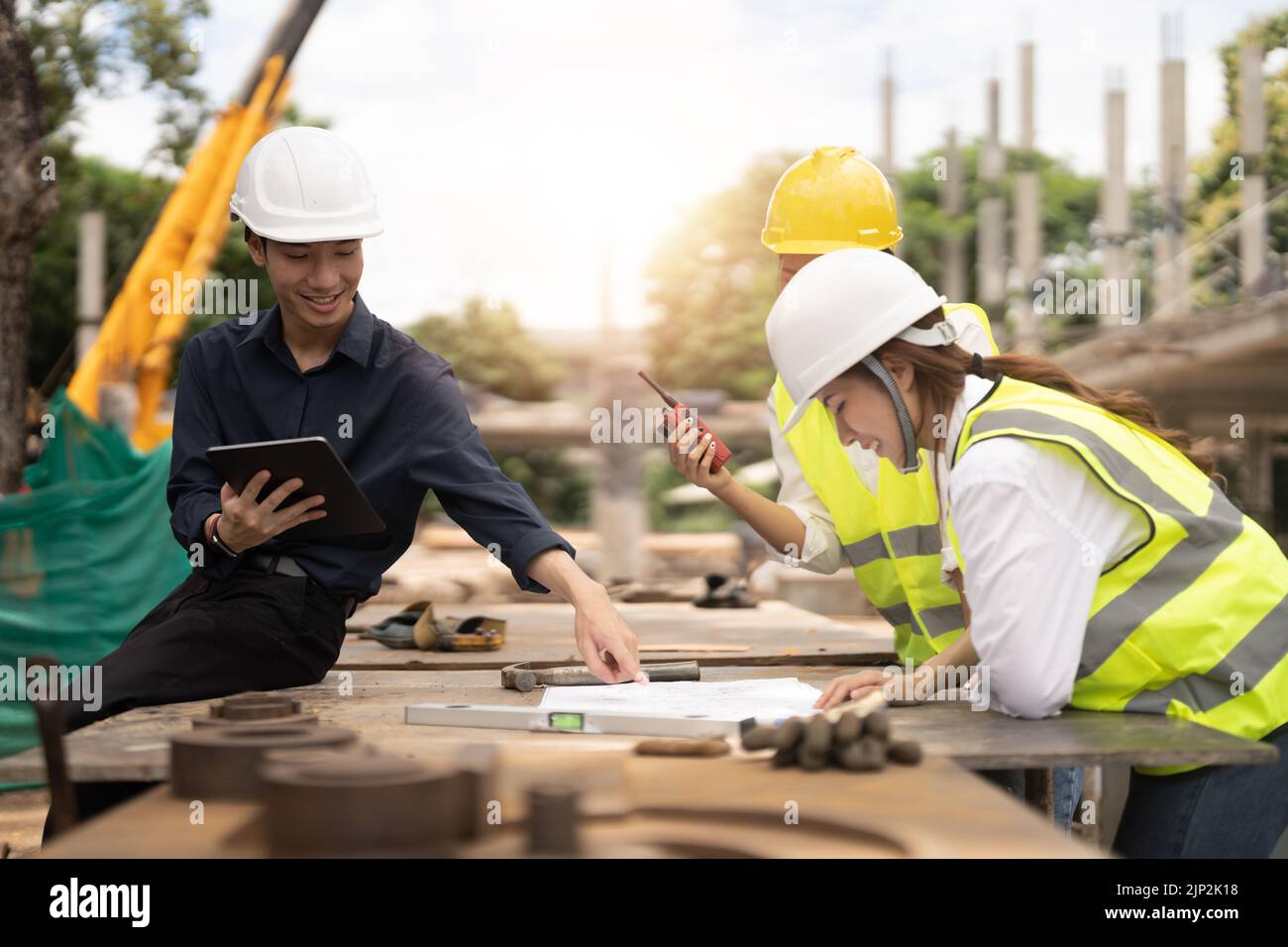 Young asian architects and engineer discussing blueprints at construction site Stock Photo