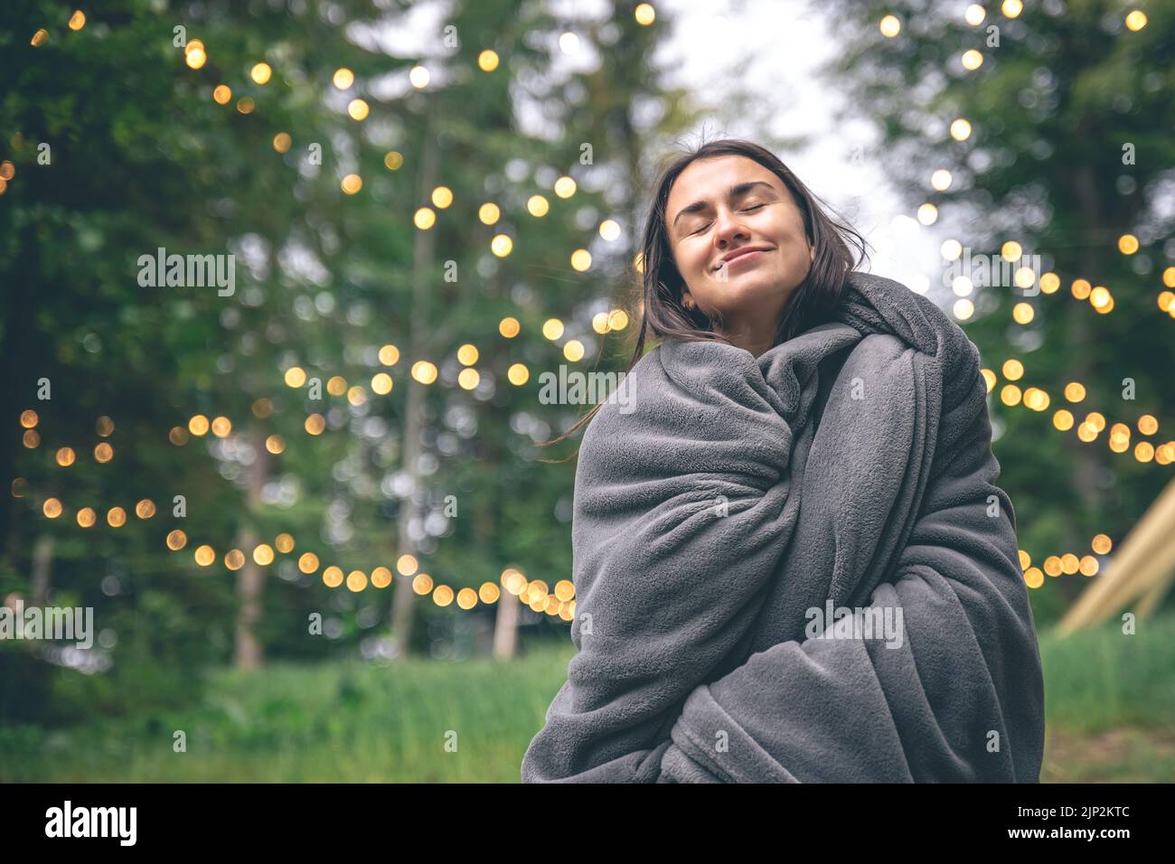A young woman wrapped in a blanket in the forest on a blurred ...