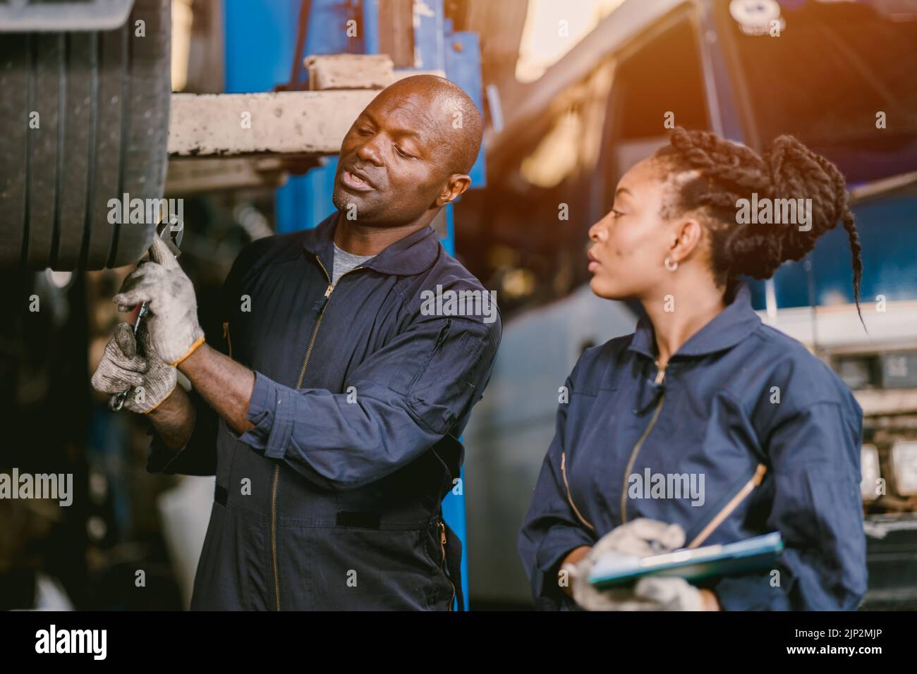 Auto garage worker Black African working together to fix service car vahicle wheel support together Stock Photo