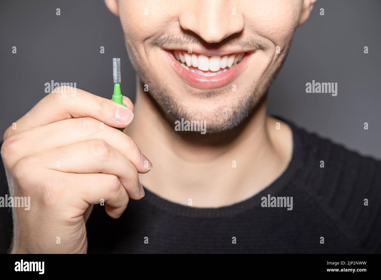 Man hold handle of interdental brush in his hands and smile into camera
