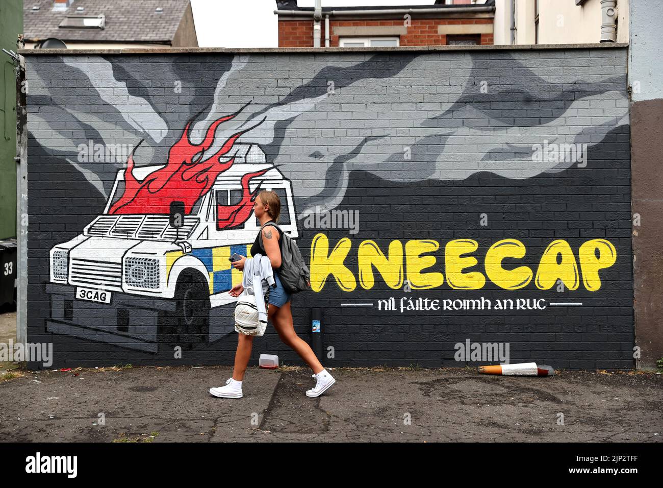 A person walks past Irish language rap group Kneecap's mural of a burning police Land Rover on Hawthorn Street in Belfast. There have been calls for political leadership after a series of incidents across the weekend, including pro-IRA chants at a concert in west Belfast. The Wolfe Tones played their annual gig to close Feile an Phobail in west Belfast on Sunday evening. Picture date: Monday August 15, 2022. Stock Photo